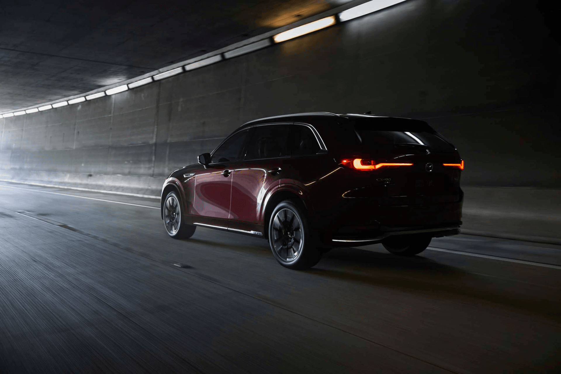 Vue 3/4 arrière du Mazda CX-90 MHEV 2025 roulant dans un tunnel.