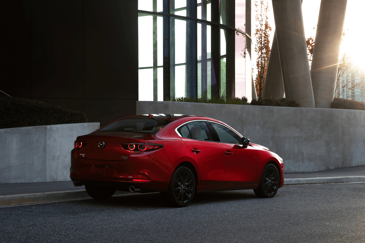 Vue 3/4 arrière de la Mazda3 2024 rouge à l'extérieur.