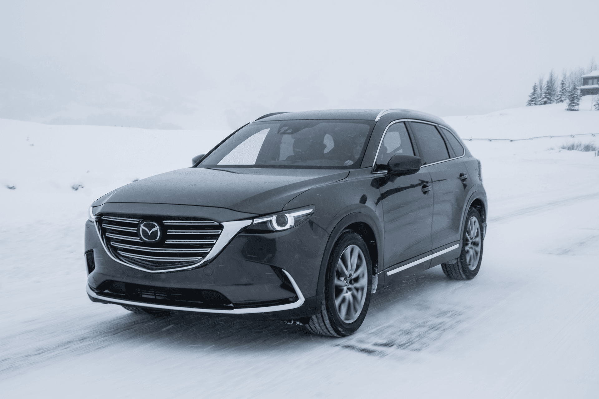 Mazda CX-9 noir roulant sur la neige en montagne